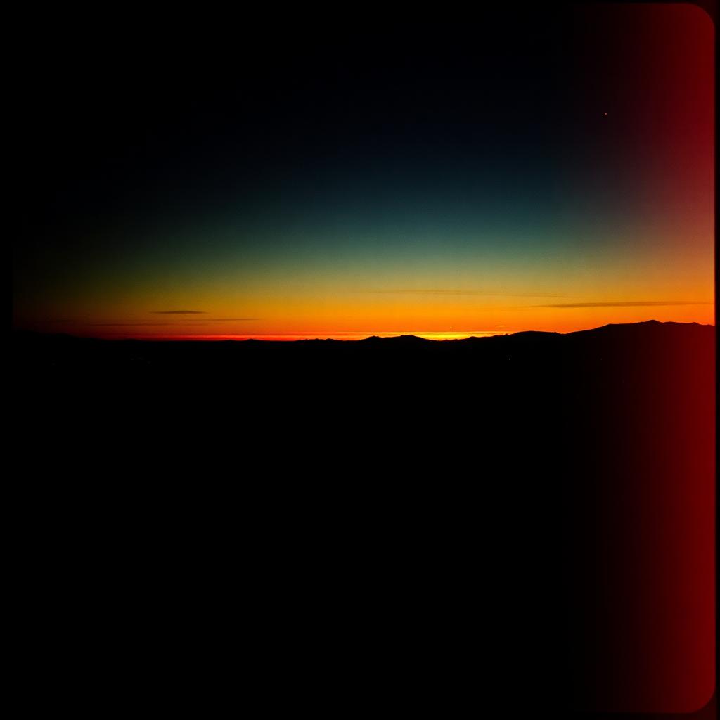 Warmer Sonnenuntergang über einer weiten Bergsilhouette